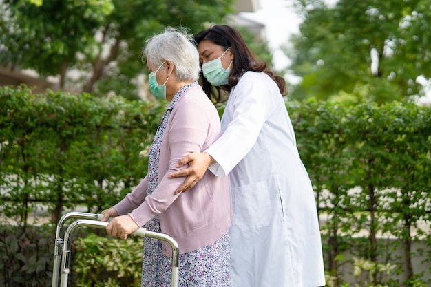 Asiatische ältere Frau gehen mit Gehhilfe und tragen eine Gesichtsmaske, um Covid19 Coronavirus zu schützen