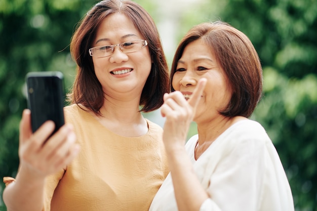 Asiatische ältere Frauen, die ihren Freund anrufen, wenn sie im Freien stehen