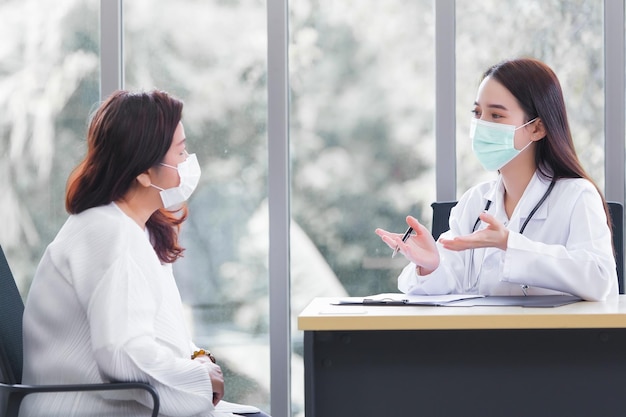 Asiatische ältere Frauen konsultieren einen professionellen Arzt über ihr Symptom im Untersuchungsraumkrankenhaus