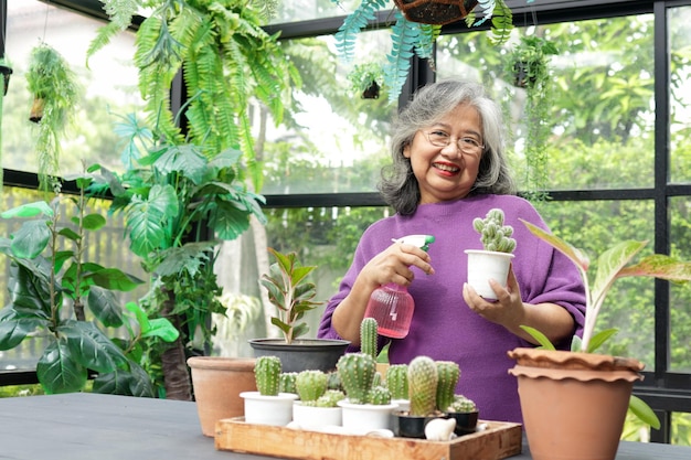 Foto asiatische ältere frauen leben zu hause, sie gießt die bäume und pflanzt gerne einen baum