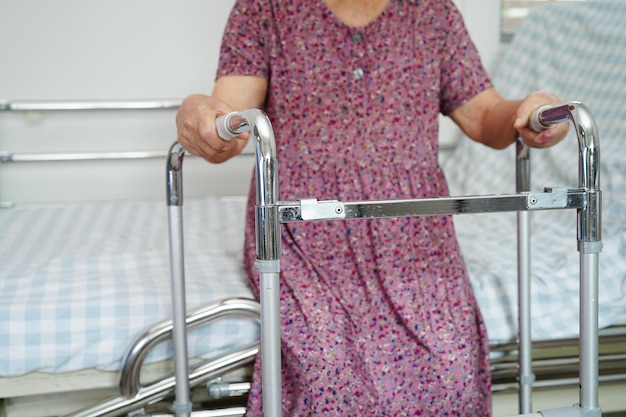 Asiatische ältere Frauen mit Behinderungen gehen mit Rollator im medizinischen Konzept des Pflegekrankenhauses