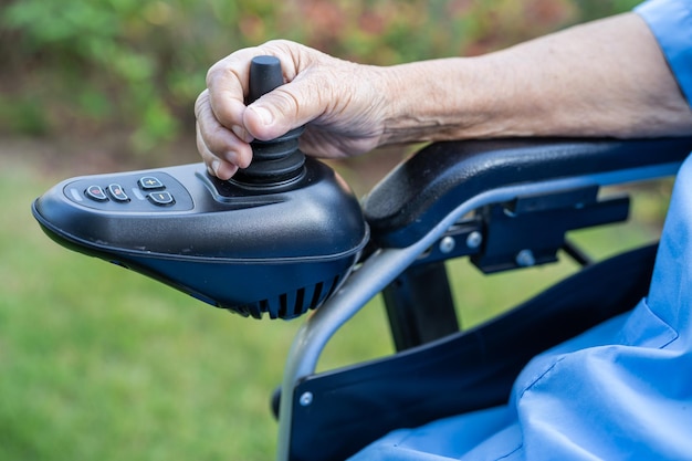 Asiatische ältere oder ältere alte Dame Patientin auf elektrischem Rollstuhl mit Fernbedienung in der Krankenstation, gesundes, starkes medizinisches Konzept