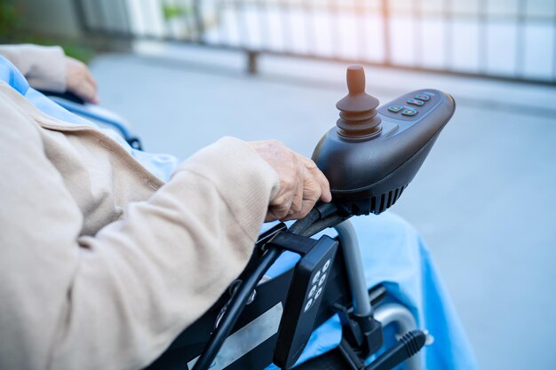 Asiatische ältere oder ältere alte Dame Patientin auf elektrischem Rollstuhl mit Fernbedienung in der Krankenstation, gesundes, starkes medizinisches Konzept