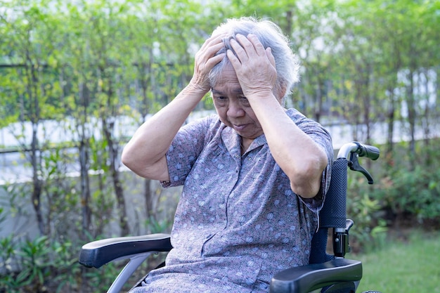 Asiatische ältere oder ältere alte Dame Patientin Kopfschmerzen beim Sitzen auf dem Bett in der Krankenstation, gesundes, starkes medizinisches Konzept