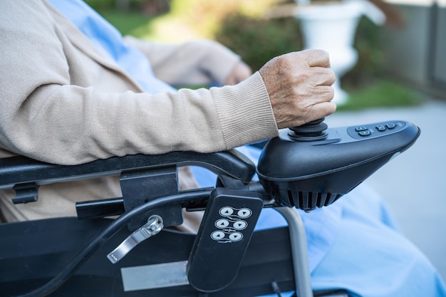 Asiatische ältere oder ältere Patientin der alten Dame auf Elektrorollstuhl mit Fernbedienung auf der Krankenstation, gesundes, starkes medizinisches Konzept