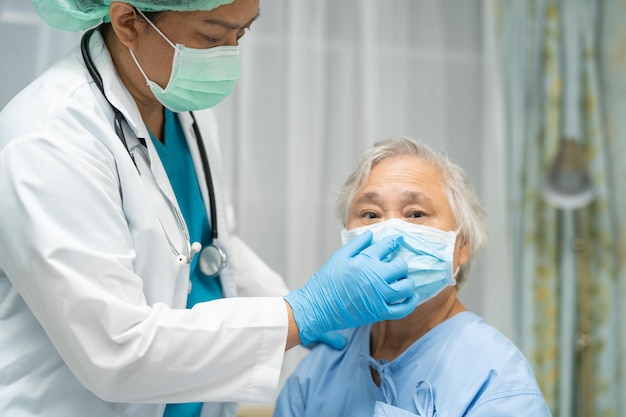 Asiatische ältere oder ältere Patientin einer alten Dame, die eine Gesichtsmaske trägt, die im Krankenhaus neu normal ist, um die Sicherheitsinfektion Covid19 Coronavirus zu schützen