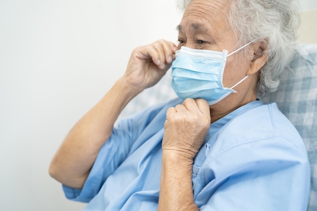 Asiatische ältere Patientin mit Maske zum Schutz von Coronavirus