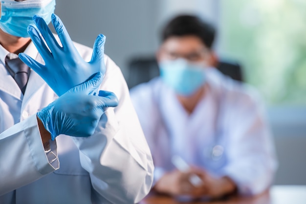 Asiatische Ärzte tragen blaue medizinische Handschuhe und medizinische Masken, um Infektionen der Herzkranzgefäße zu verhindern