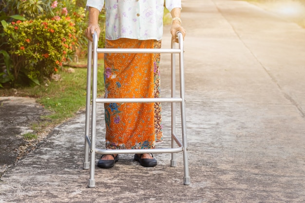 Asiatische alte Frau, die mit ihren Händen auf einem Wanderer steht