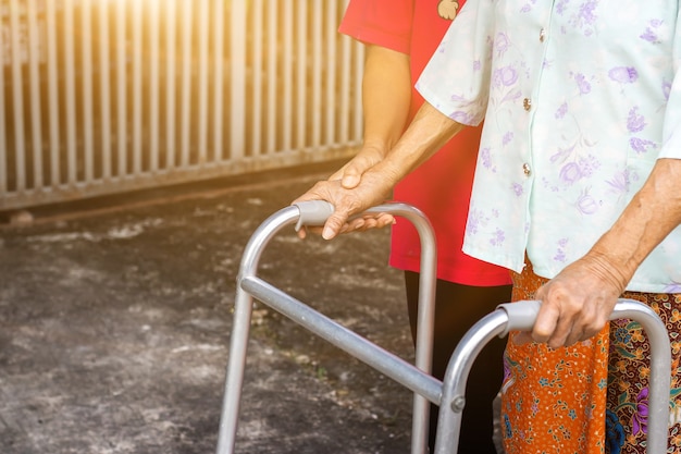 Asiatische alte Frau, die mit ihrer Hand auf einem Wanderer mit der Hand der Tochter steht