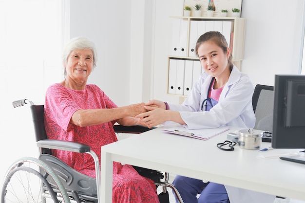 Asiatische alte Patientin im Gespräch mit Ärztinnen im Klinikbürokrankenhaus