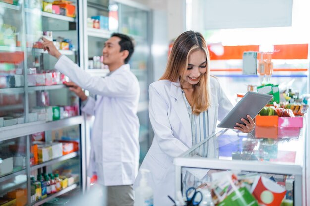 Foto asiatische apothekerin in uniform beim aufräumen des fensters in einer apotheke