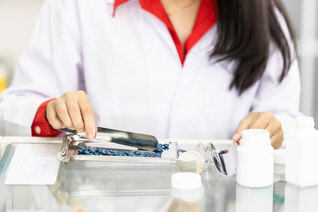 Asiatische Apothekerin zählt Pillen in der Apotheke mit Pillenzählschalen aus Edelstahl Bereiten Sie die Arzneimittelpackung für den Patienten in der Apotheke gesund und medizinisch vor