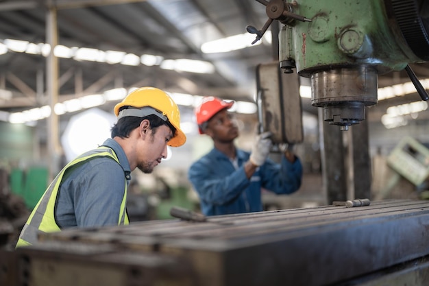 asiatische arbeiter und afrikanische mannfabriken, die im schulungspersonal für stahlschwermaschinenbau arbeiten