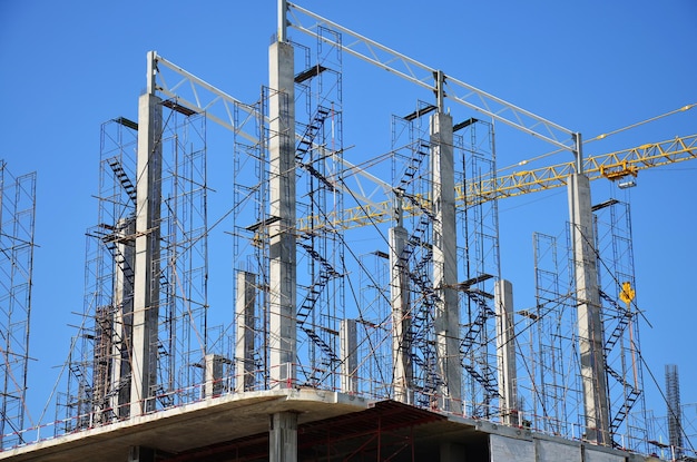 Asiatische Arbeiter und thailändische Arbeiter verwenden Maschinen und schwere Maschinen, die Baumeister bauen, neue Strukturturm-Hochhausgebäude auf Gerüsten auf der Baustelle in der Hauptstadt von Bangkok, Thailand