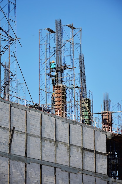 Asiatische Arbeiter und thailändische Arbeiter verwenden Maschinen und schwere Maschinen, die Baumeister bauen, neue Strukturturm-Hochhausgebäude auf Gerüsten auf der Baustelle in der Hauptstadt von Bangkok, Thailand