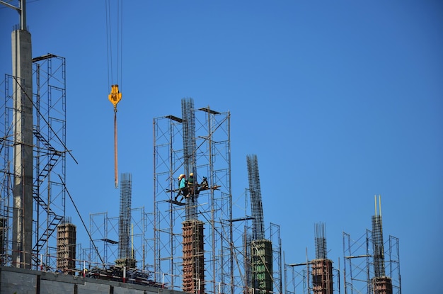 Asiatische Arbeiter und thailändische Arbeiter verwenden Maschinen und schwere Maschinen, die Baumeister bauen, neue Strukturturm-Hochhausgebäude auf Gerüsten auf der Baustelle in der Hauptstadt von Bangkok, Thailand