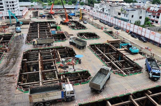 Asiatische Arbeiter und thailändische Arbeiter verwenden Maschinen und schwere Maschinen, die Baumeister bauen, neue Strukturturm-Hochhausgebäude auf Gerüsten auf der Baustelle in der Hauptstadt von Bangkok, Thailand