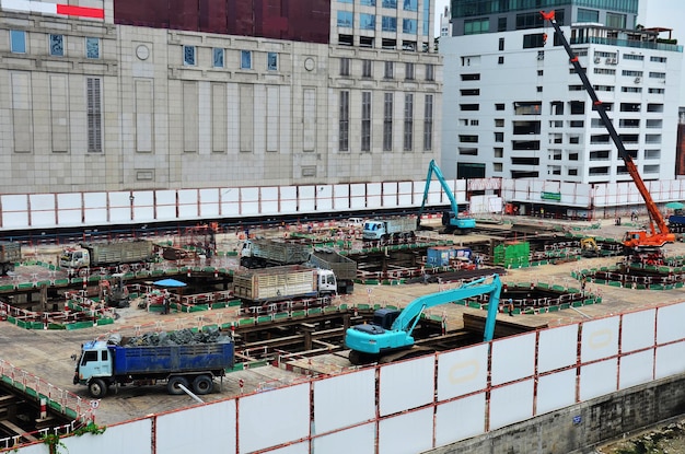 Asiatische Arbeiter und thailändische Arbeiter verwenden Maschinen und schwere Maschinen, die Baumeister bauen, neue Strukturturm-Hochhausgebäude auf Gerüsten auf der Baustelle in der Hauptstadt von Bangkok, Thailand