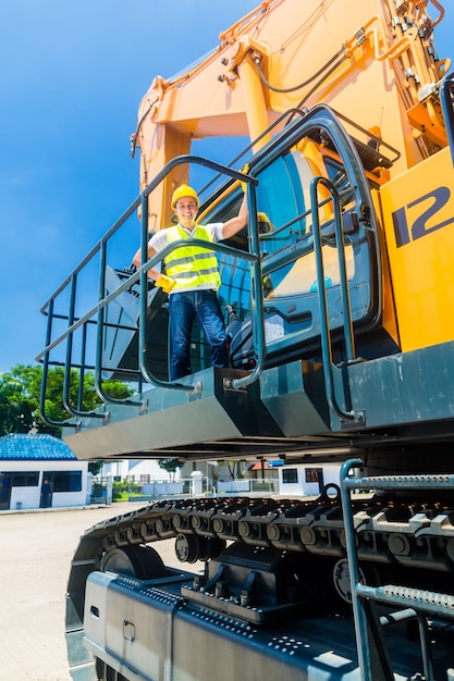 Asiatische Arbeitskraft auf SchaufelbaggerBaustelle