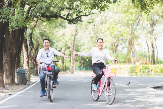 Asiatische asiatische Paare fahren glücklich Fahrrad im Garten und haben Spaß an den Wochenenden.