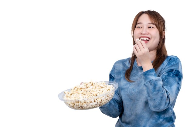 Asiatische attraktive junge fette Frau, die eine Schüssel Popcornlächeln hält und genießt, Popcorn zu essen