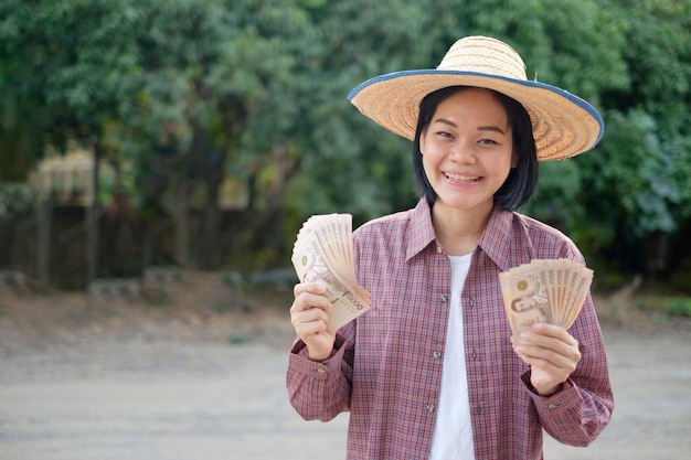 Asiatische Bäuerin lächelt Gesicht und hält Thailand-Banknotengeld