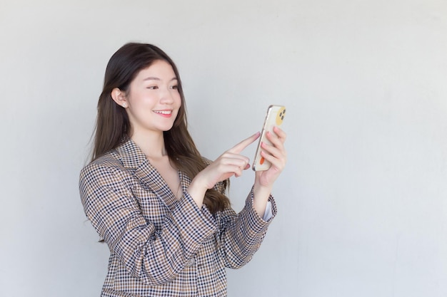 Asiatische Berufsfrau mit schwarzen langen Haaren, die einen karierten Anzug trägt, während sie mit Erfolg handelt