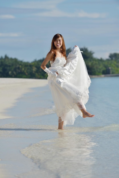 Asiatische Braut mit Schleier am Strand im Himmel und im blauen Meer. Flitterwochen auf der fantastischen Insel im Sommer