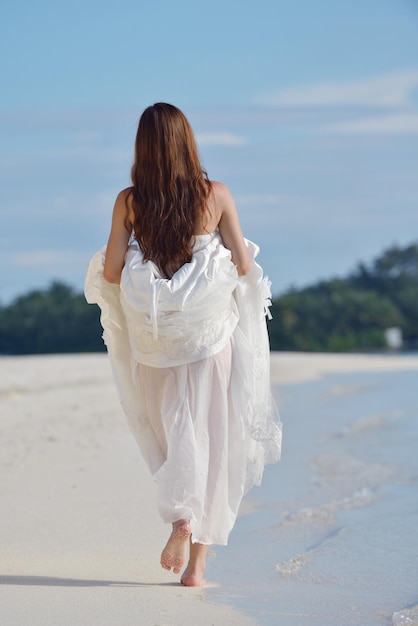 Asiatische Braut mit Schleier am Strand im Himmel und im blauen Meer. Flitterwochen auf der fantastischen Insel im Sommer