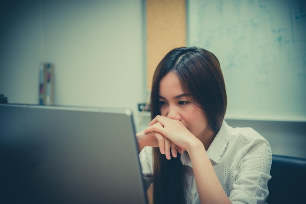 Asiatische Bürofrau Stress von der Arbeit am Schreibtisch mit Laptop