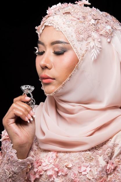 Asiatische charmante muslimische arabische Braut in Lace Bead Embroidery Sweet Pink altes Rosenhochzeitskleid und Hijab-Kopftuch, Nahaufnahme auf Fashion Make-up Eyes Face, Studiobeleuchtung schwarzer Hintergrund isoliert.