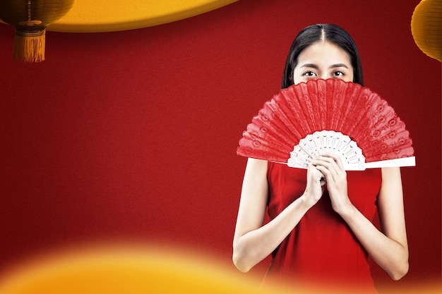 Asiatische Chinesin in einem Cheongsam-Kleid mit Fächer feiert das chinesische Neujahr. Frohes chinesisches Neujahr