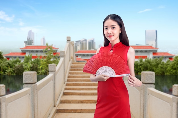 Asiatische Chinesin in einem Cheongsam-Kleid mit Fächer feiert das chinesische Neujahr. Frohes chinesisches Neujahr