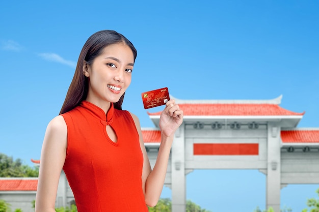 Asiatische Chinesin in einem Cheongsam-Kleid mit Kreditkarte. Frohes chinesisches Neujahr