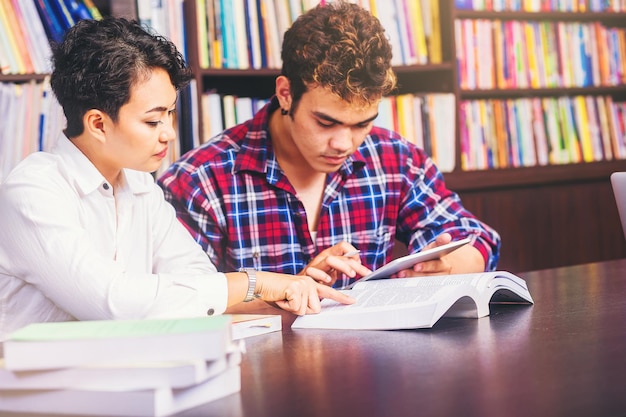 Asiatische College-Studenten, die sitzen und lesen und mit Freunden Tutor-Bücher untersuchen