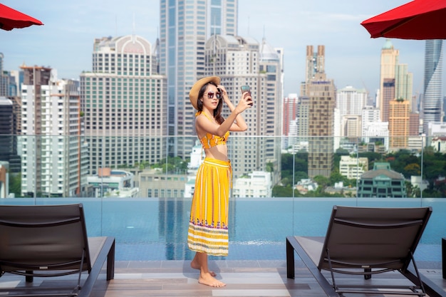 Asiatische dame genießen selfie im schwimmbad auf dem dach des hotels in bangkok stadt, thailand