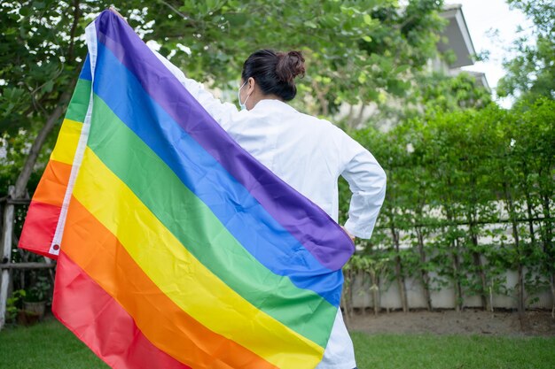 Asiatische Dame mit Regenbogen-Flagge, Symbol des LGBT-Pride-Monats, feiert jährlich im Juni soziale Menschenrechte für Homosexuelle, Lesben, Bisexuelle und Transsexuelle.