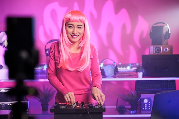 Asiatische DJs, die Techno-Songs mit einem Mischpult aufführen, während sie mit der Smartphone-Kamera aufnehmen, und Musikvideos für Abonnenten auf ihren Kanal stellen. Künstler mischen nachts im Club