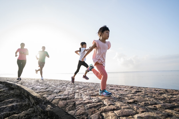 Asiatische Eltern und Kinder, die Sport im Freien laufen lassen