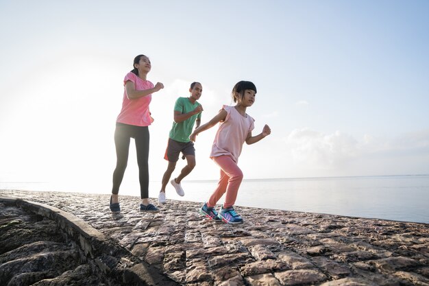 Asiatische Eltern und Kinder, die Sport im Freien laufen lassen