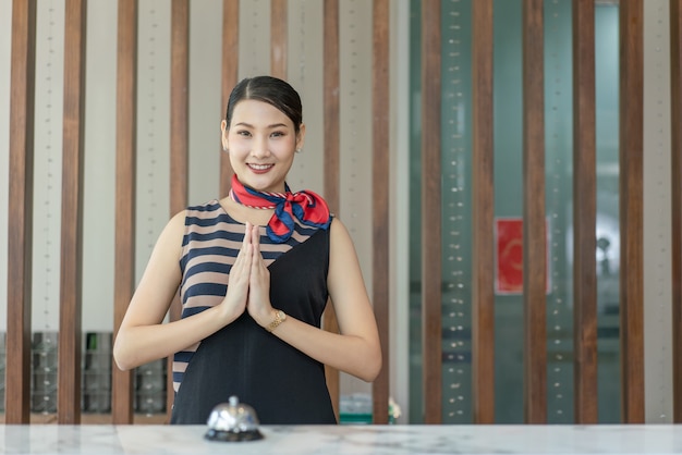 Asiatische Empfangsdame lächelt und respektiert ausländische Gäste, die am Hotelschalter einchecken?