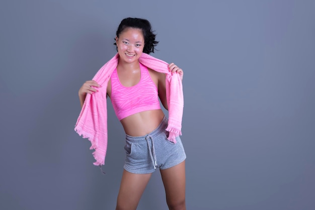 Asiatische ethnische Frau in Sportbekleidung mit Handtuch um den Hals, isoliert vom Hintergrund