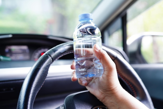 Asiatische Fahrerin hält kaltes Wasser zum Trinken im Auto gefährlich und riskiert einen Unfall