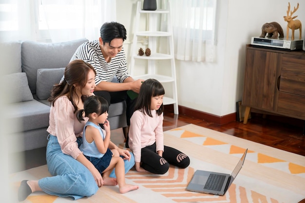 Asiatische Familie mit Kindern, die zu Hause einen Laptop verwenden