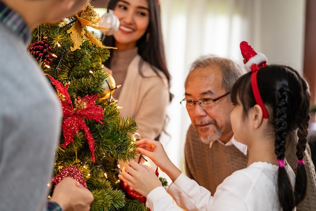 Asiatische Familie mit mehreren Generationen, die einen Weihnachtsbaum schmückt