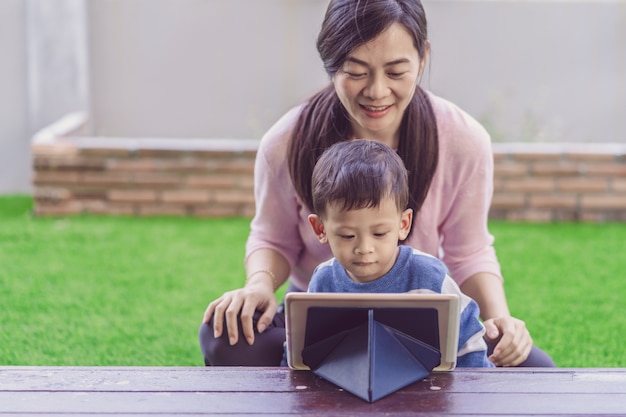 Asiatische Familie mit Sohn schauen die Karikatur über Technologietablette und spielen zusammen