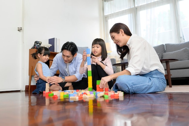 Asiatische Familie mit spielenden und bauenden Kindern aus bunten Holzspielzeugblöcken