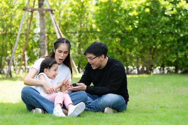 Asiatische Familie mit Vater, Mutter und Tochter, die sich glücklich im Garten des Hauses amüsieren