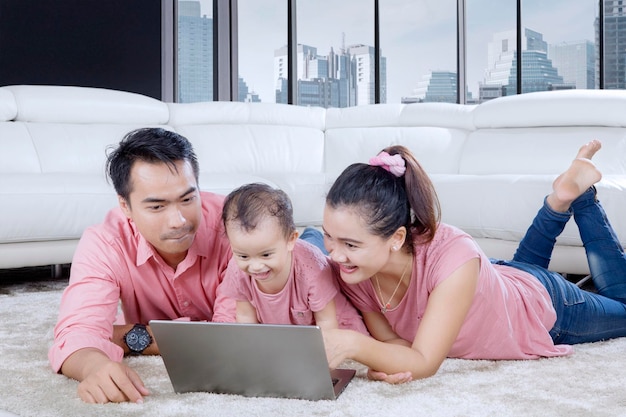 Asiatische Familie spielt mit Laptop auf dem Teppich